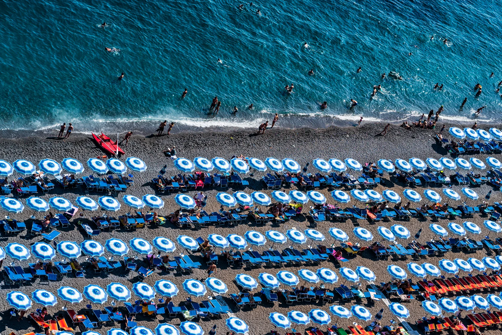 Bãi biển Spiaggia Grand ở Positano đông đảo với hàng cây dù và thuyền trong vịnh